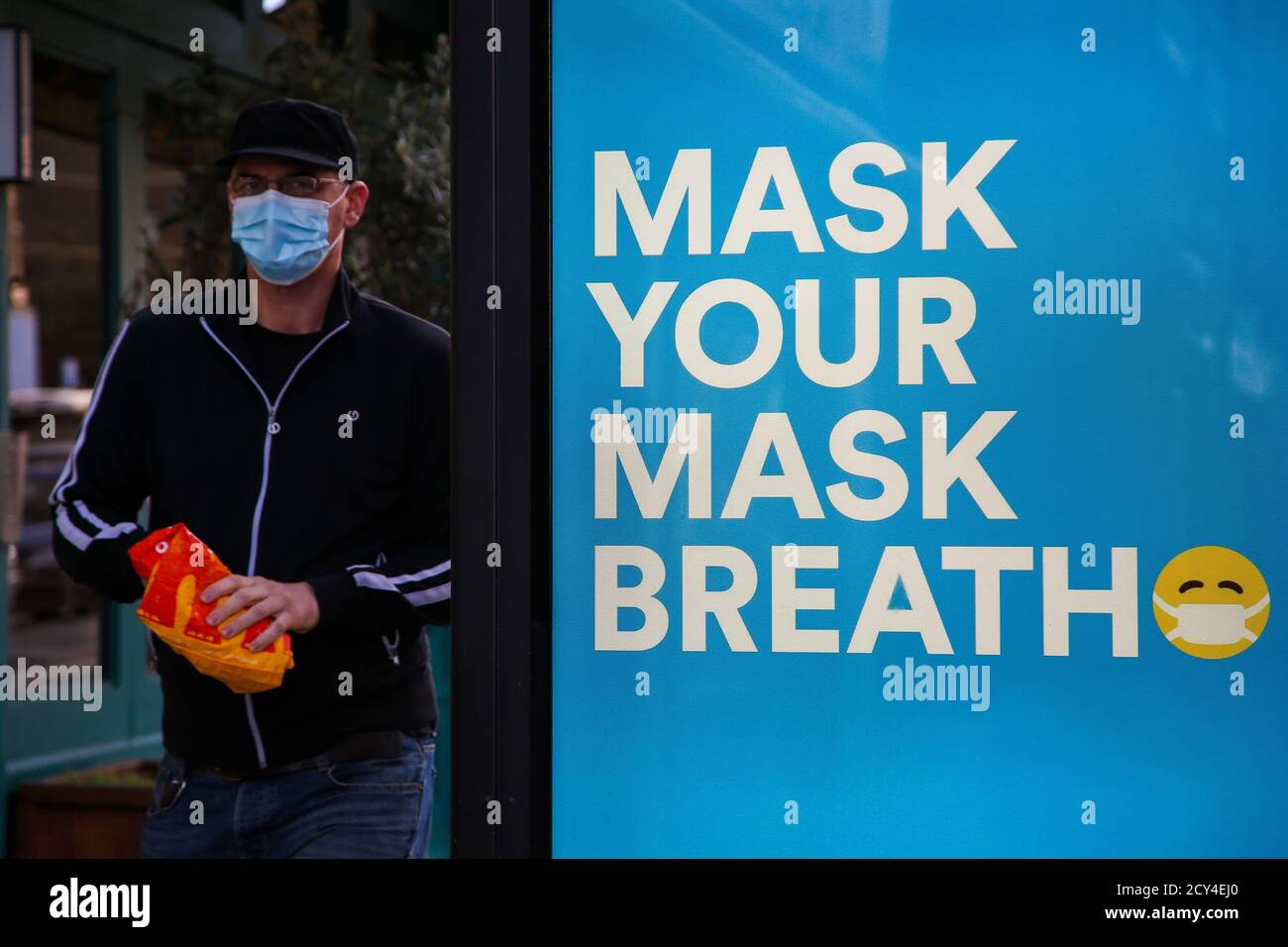 A man wearing a face mask as a preventive measure walks past 'Mask Your