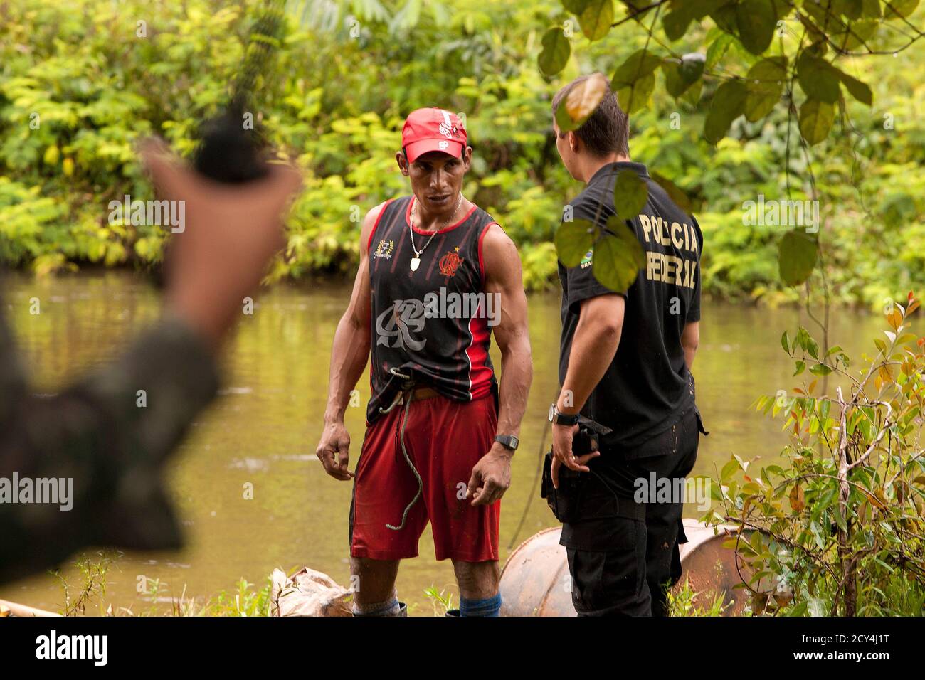 Brazilian Federal Police officers detain a wildcat miner to question him about his activities, during a patrol for drug smugglers and illegal gold mines along the Cassipore River near the border with French Guiana, in this picture taken May 9, 2012. Brazil's Army began Operation Agate with the Federal Police, Customs, the National Aviation Agency, and the government's environmental police force (IBAMA), along a large part of the northern border to combat smuggling and environmental crimes, according to an Army communique. Picture taken May 9, 2012. REUTERS/Paulo Santos (BRAZIL - Tags: MILITARY Stock Photo
