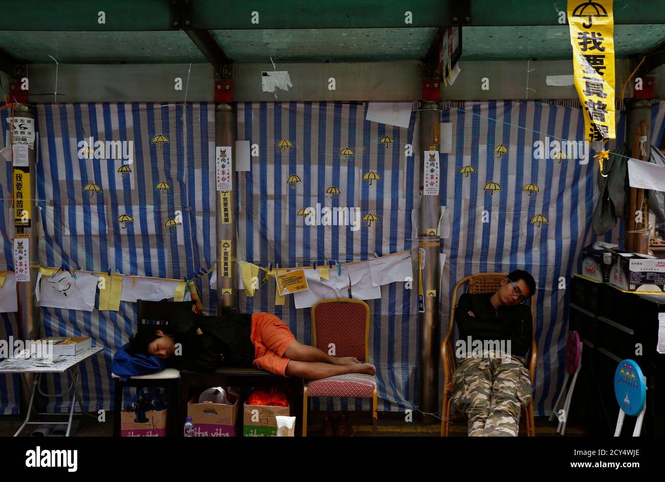 Pro-democracy protesters sleep at a bus stop on the blocked Nathan Road as part of the Occupy Central civil disobedience movement at Mongkok shopping district in Hong Kong November 12, 2014. Hong Kong's acting chief executive on Tuesday called on pro-democracy protesters to clear sites they have occupied for more than six weeks and warned holdouts they could face arrest, a move that could swell protest numbers. The banner on top right reads 'I want real universal suffrage'.     REUTERS/Bobby Yip  (CHINA - Tags: POLITICS CIVIL UNREST) Stock Photo