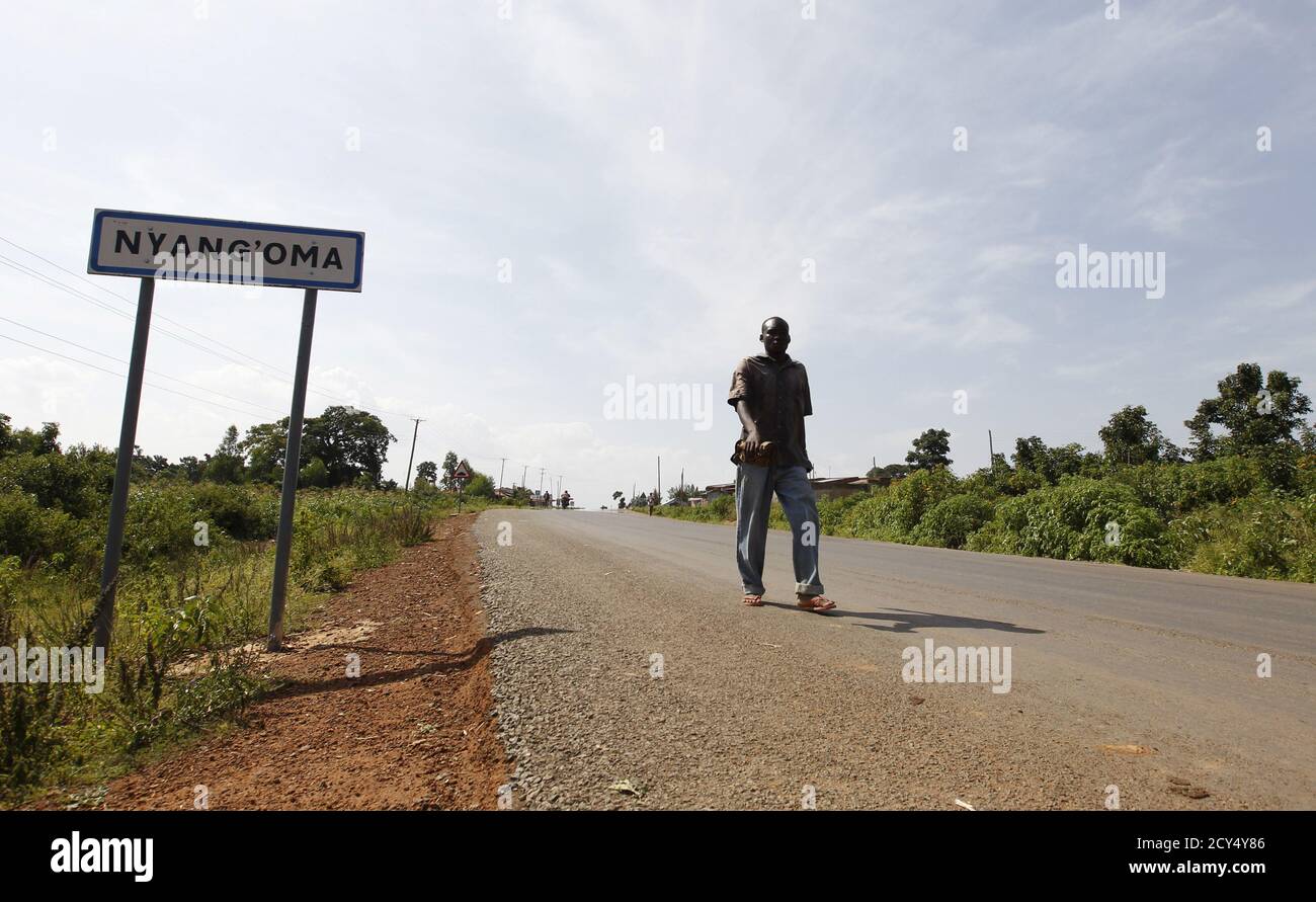 A man walks past a road-signage introducing Nyang'oma village, the U.S. President Barack Obama's ancestral village of Nyang'oma Kogelo, west of Kenya's capital Nairobi, July 16, 2015. Obama visits Kenya and Ethiopia in July, his third major trip to Sub-Saharan Africa after travelling to Ghana in 2009 and to Tanzania, Senegal and South Africa in 2011. He has also visited Egypt, in North Africa, and South Africa for Nelson Mandela's funeral. Obama will be welcomed by a continent that had expected closer attention from a man they claim as their son, a sentiment felt acutely in the Kenyan village  Stock Photo