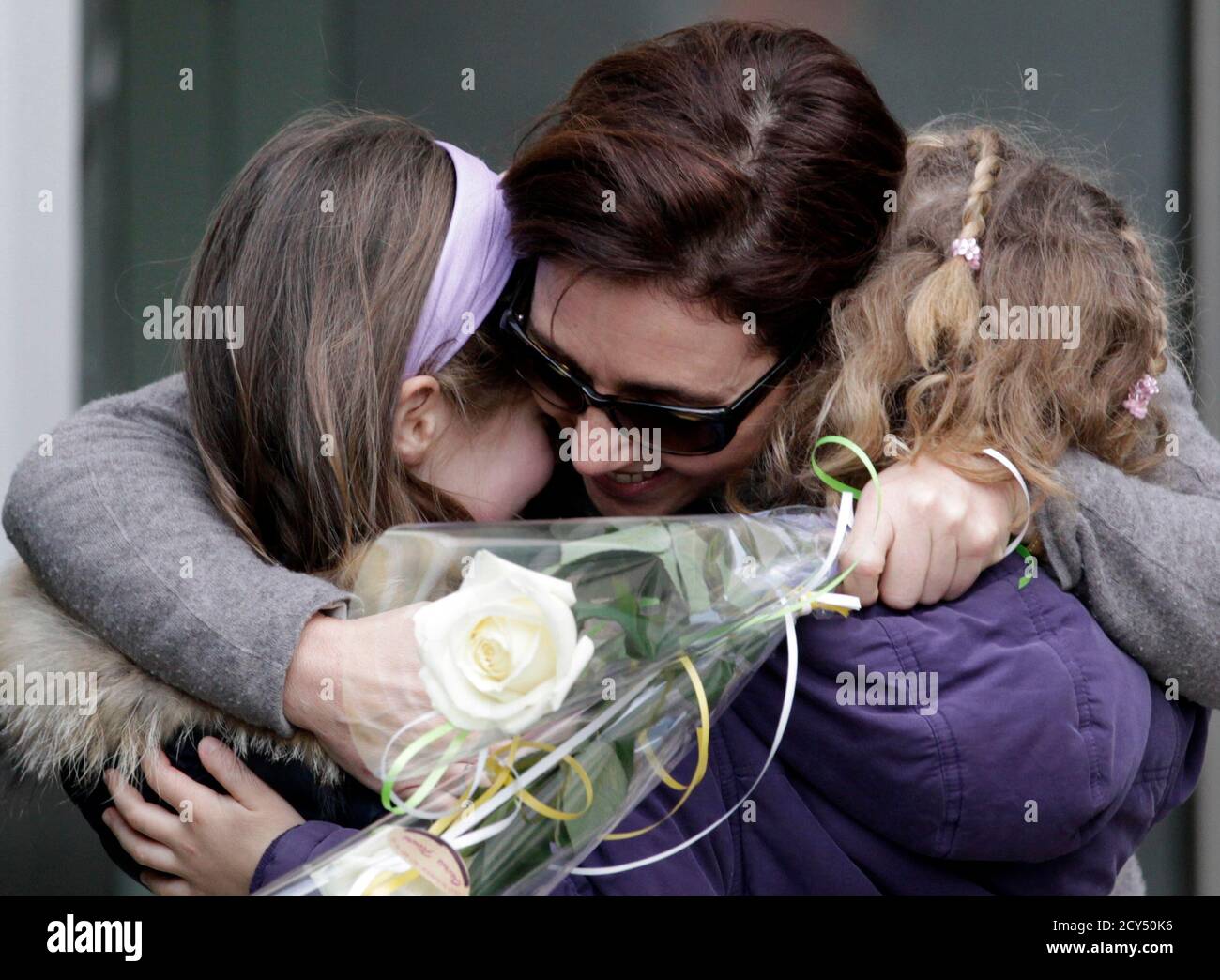 Irina Lucidi (C) mother of missing six-year-old twins Alessia and Livia  Schepp, hugs two unidentified girls after receiving flowers at the end of a  support walk in St-Sulpice February 23, 2011. Rescuers