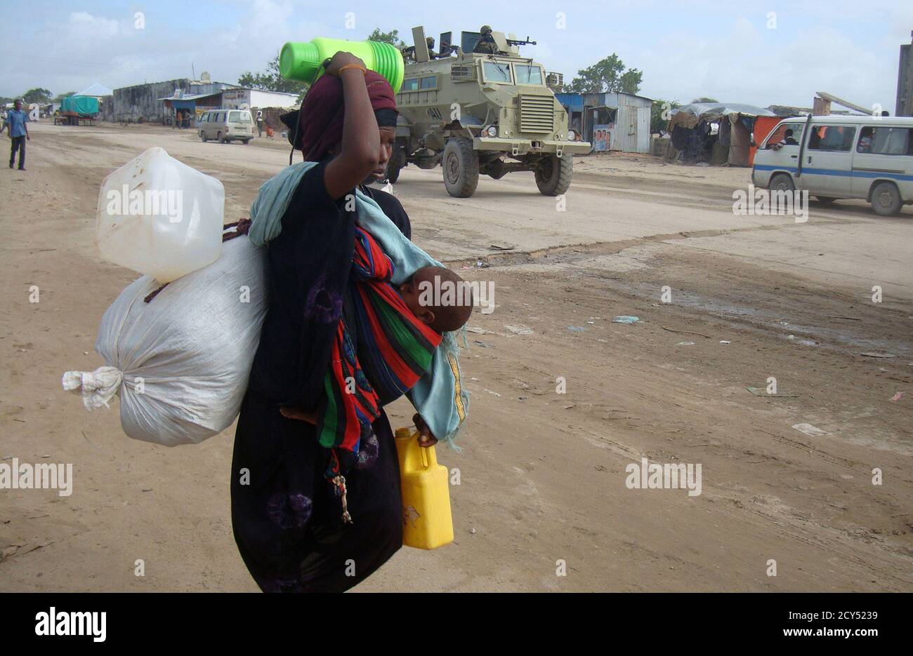A newly displaced Somali woman carries her child and belongings as they arrive in the capital Mogadishu, August 3, 2011. The Horn of Africa food crisis shows the need to provide the world's poor with better access to family planning as part of efforts to prevent future tragedies, the head of the United Nations Population Fund (UNFPA) said. REUTERS/Feisal Omar (SOMALIA - Tags: SOCIETY ENVIRONMENT DISASTER) Stock Photo