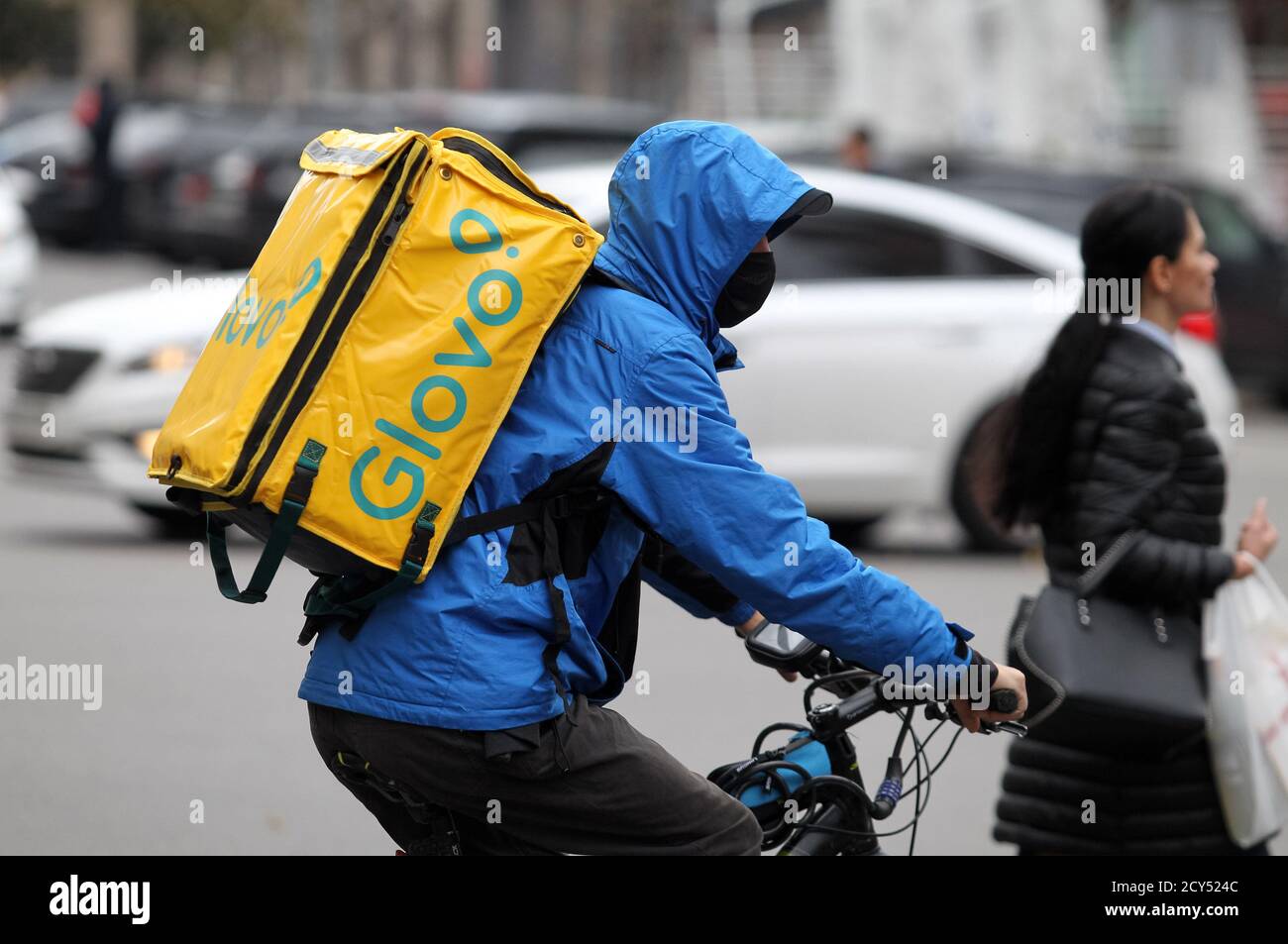 An employee of food delivery company Glovo wearing a face mask rides