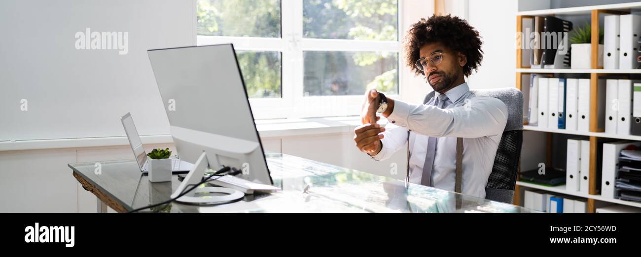 Black Man Stretching At Office Desk At Work Stock Photo