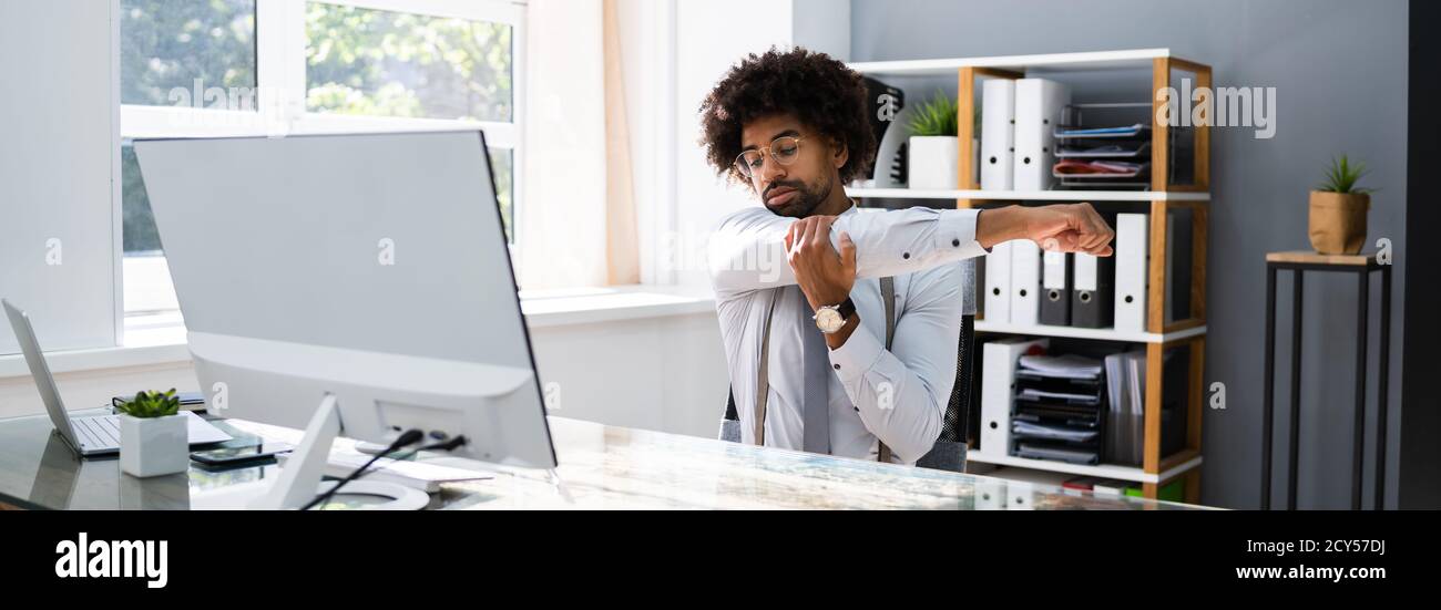 Black Man Stretching At Office Desk At Work Stock Photo