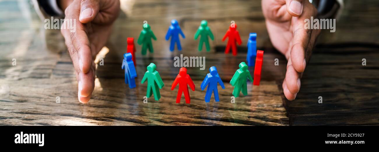 African Man Protecting Employee Figures With Hand Stock Photo