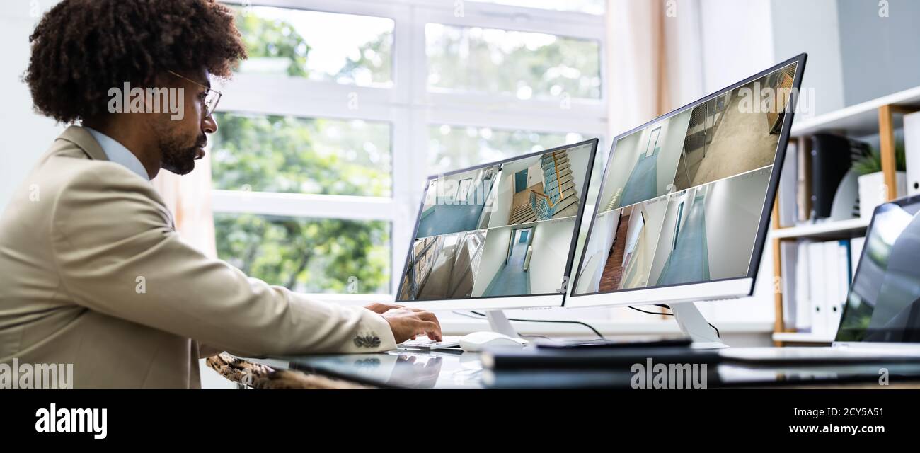Security Guard Looking At CCTV Surveillance Video Footage Stock Photo