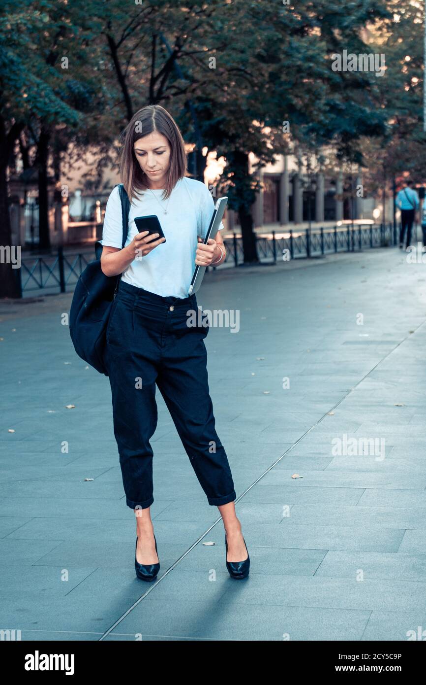 Business woman with laptop and smart phone in hands on city street. Stock Photo