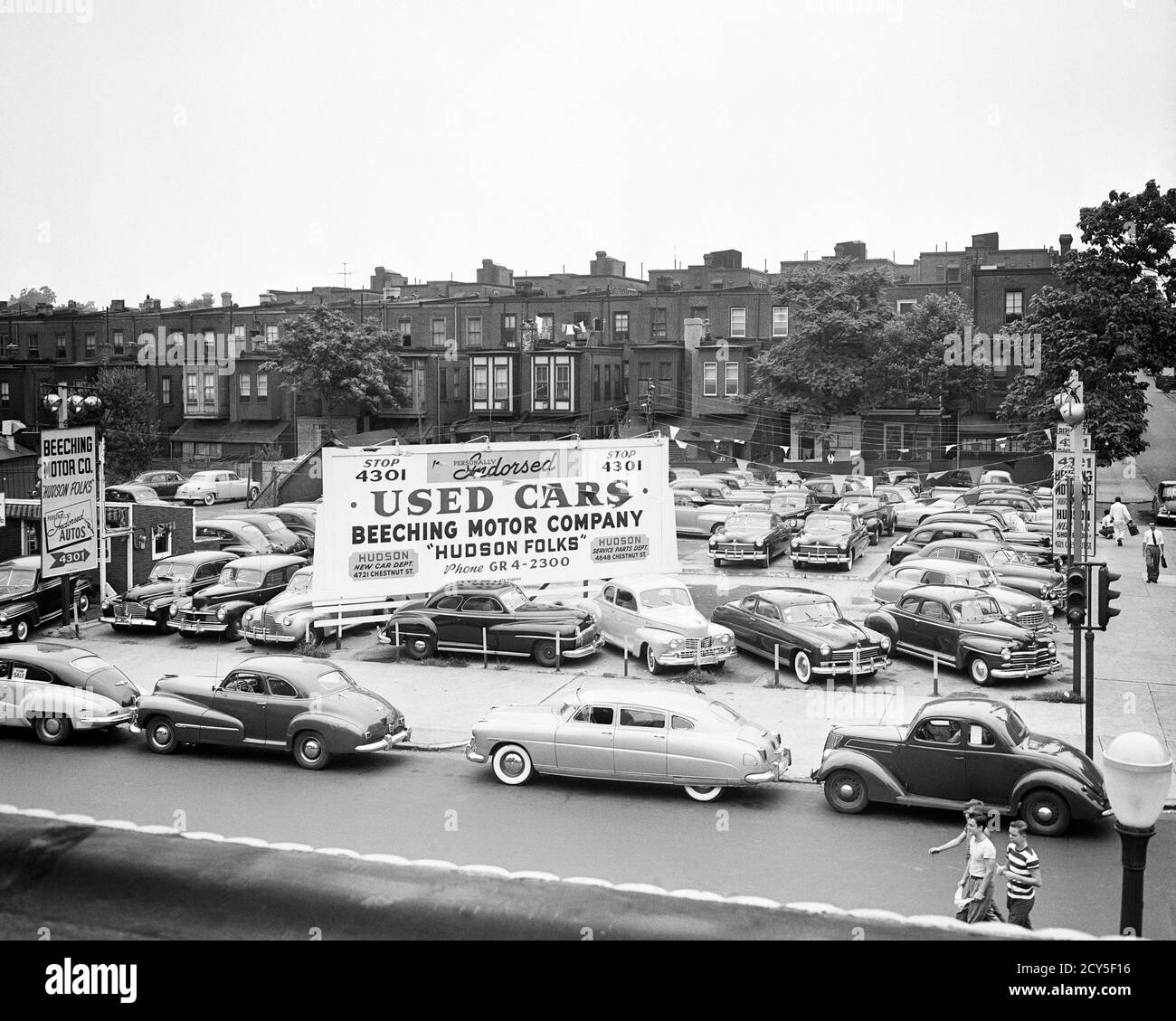 1940s 1950s USED CAR SALES LOT WITH LARGE SIGN AND SKYLINE OF ROW HOUSES PHILADELPHIA PENNSYLVANIA USA - m3264 HAR001 HARS OLD FASHIONED Stock Photo