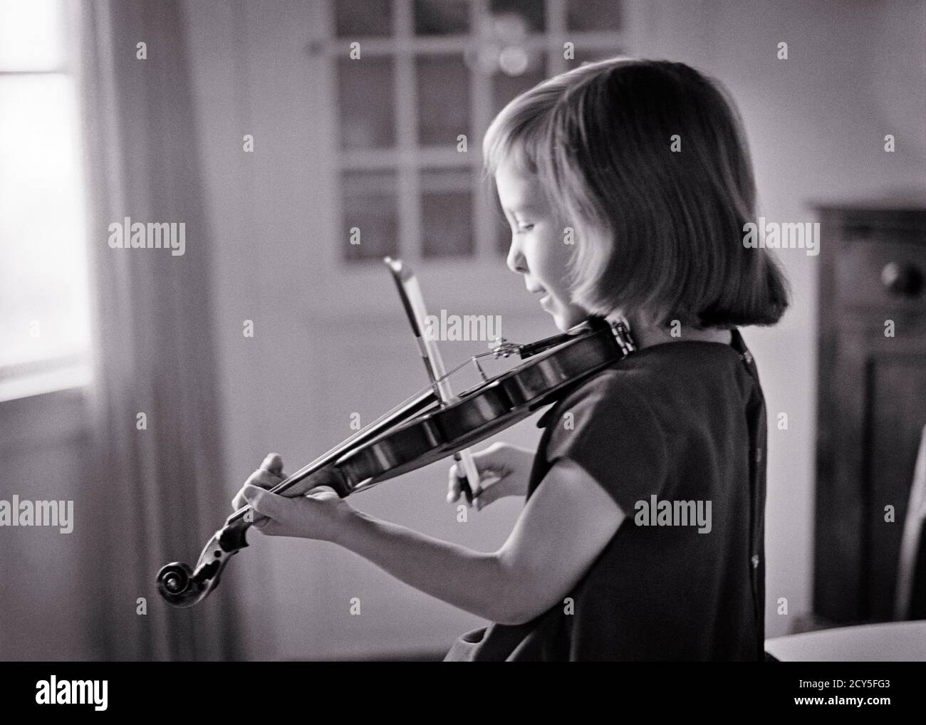 1960s PLAYING VIOLIN CHARMING LITTLE YOUNG BLOND GIRL PRACTICING LESSONS ON THREE QUARTER SIZE INSTRUMENT IN LIVING ROOM AT HOME - m7568 HAR001 HARS COPY SPACE HALF-LENGTH PRACTICE STRINGS B&W PERFORMING ARTS TEMPTATION DREAMS LESSONS SIZE RECREATION AT IN ON VIBRATION VIOLINS MUSICAL INSTRUMENT CONCEPTUAL CHARMING GROWTH JUVENILES YOUNGSTER BLACK AND WHITE CAUCASIAN ETHNICITY HAR001 OLD FASHIONED PRACTICING Stock Photo