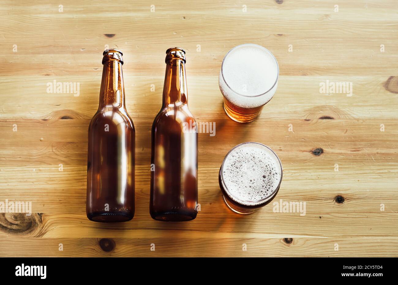 Two empty beer bottles and two glasses with beer on a wooden background, copy space, top view Stock Photo