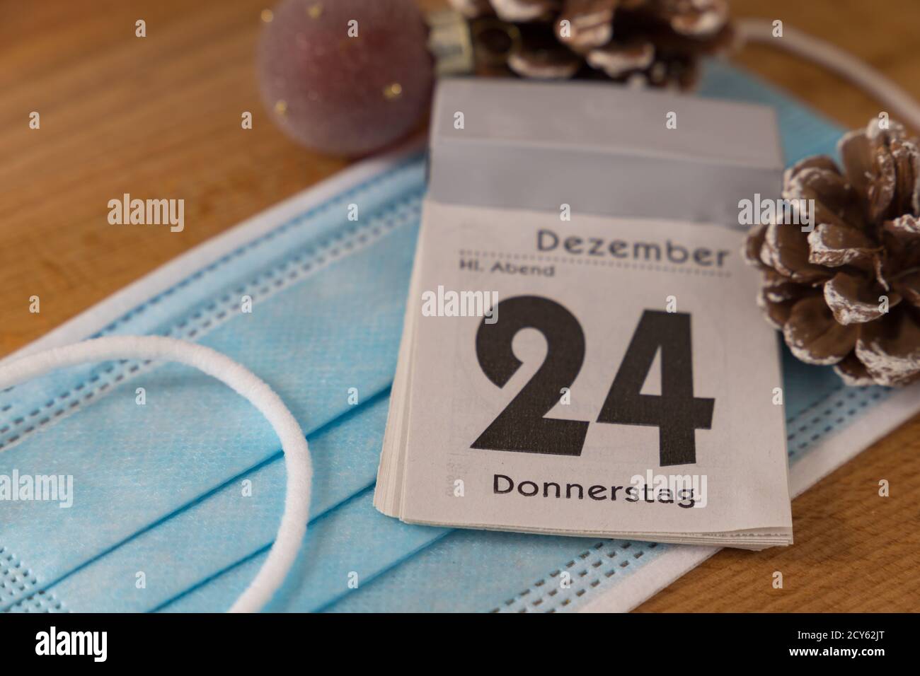calendar with german inscription of december, christmas, 24 Thursday on a face mask with christmas decoration during corona pandemic Stock Photo