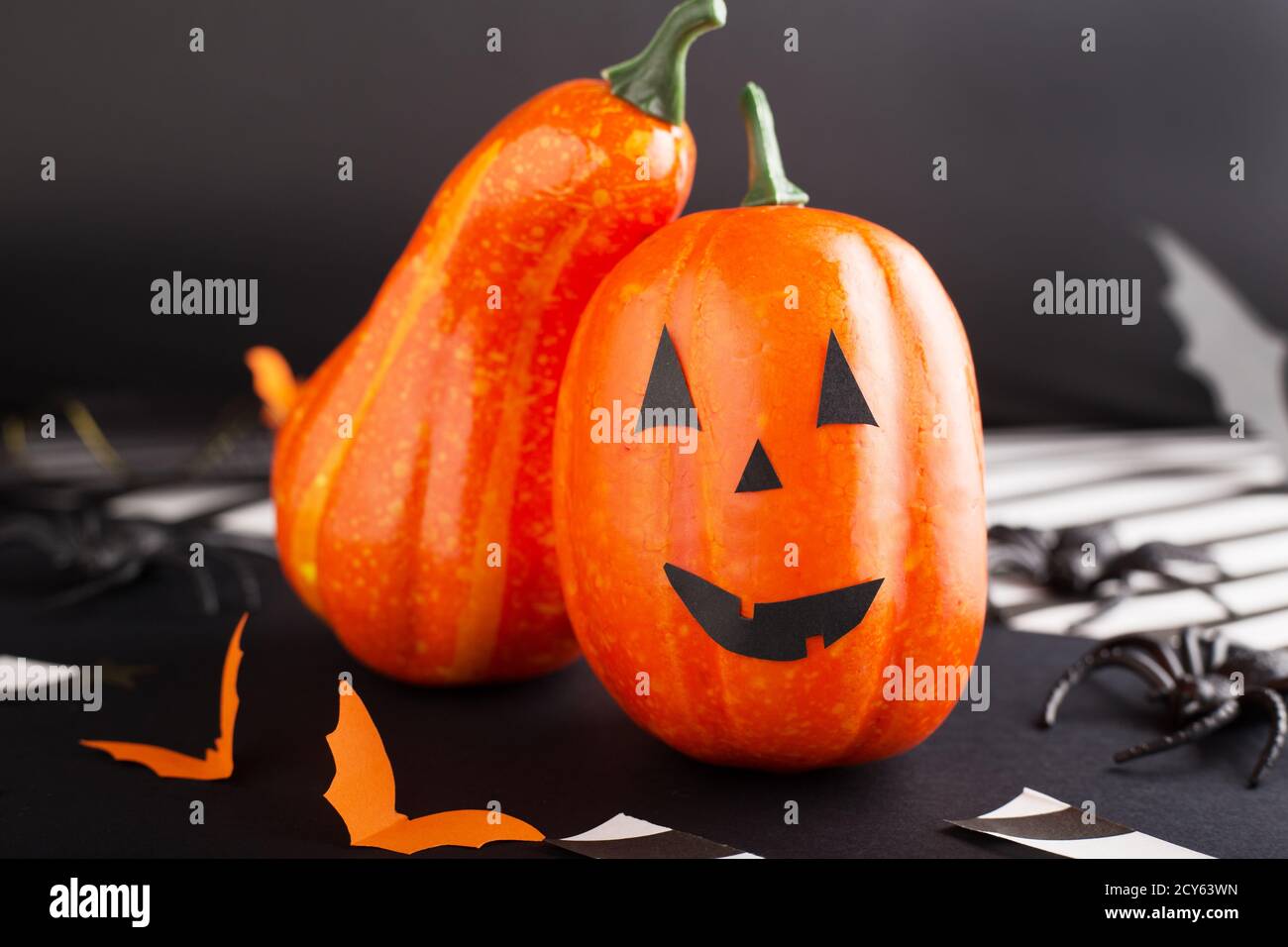 jack-o'-lantern with spider, paper bats, pumpkin ribbons, confetti on black background. Halloween party invitation, celebration. Halloween decorations Stock Photo