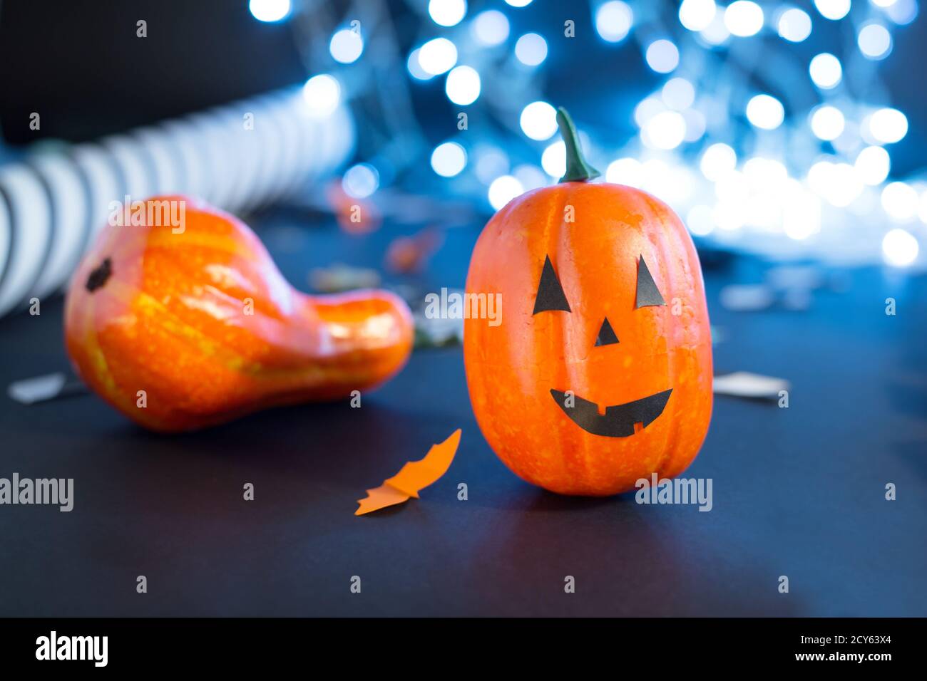 jack-o'-lantern with paper bats, pumpkin ribbons, confetti on black background with lights. Halloween party invitation, celebration. Halloween Stock Photo