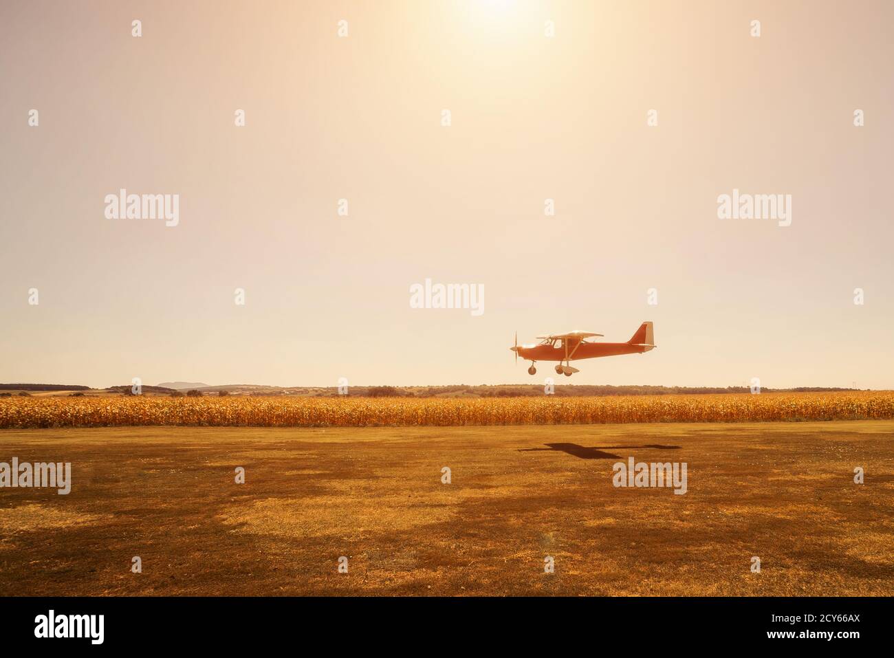 Small red plane in low pass over airstrip Stock Photo