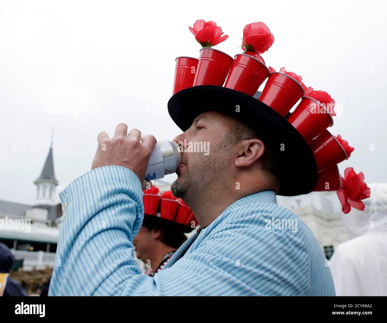 Race patron Andre Broussard enjoys a drink under his hat of red beer cups  filled with flowers bbefore the running of the 139th Kentucky Derby horse  race at Churchill Downs in Louisville,