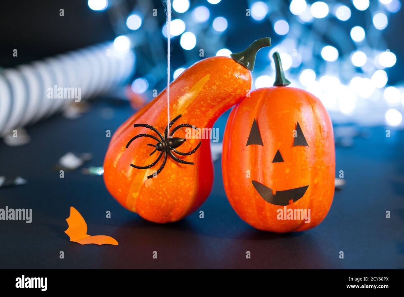 jack-o'-lantern with spider, paper bats, pumpkin ribbons, confetti on black background with lights. Halloween party invitation, celebration. Halloween Stock Photo