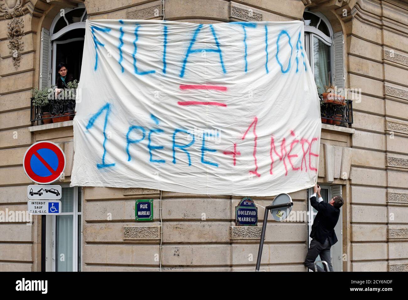 A demonstrator against gay marriage, adoption and procreation assistance hangs a banner on the streets of Paris, January 13, 2013. The banner reads: 'Filiation = 1 father + 1 mother'. Trains, buses and cars poured into Paris on Sunday bringing protesters from around France for a mass demonstration against gay marriage, a divisive reform President Francois Hollande has pledged to enact by June. REUTERS/Benoit Tessier (FRANCE - Tags: SOCIETY POLITICS CIVIL UNREST) Stock Photo