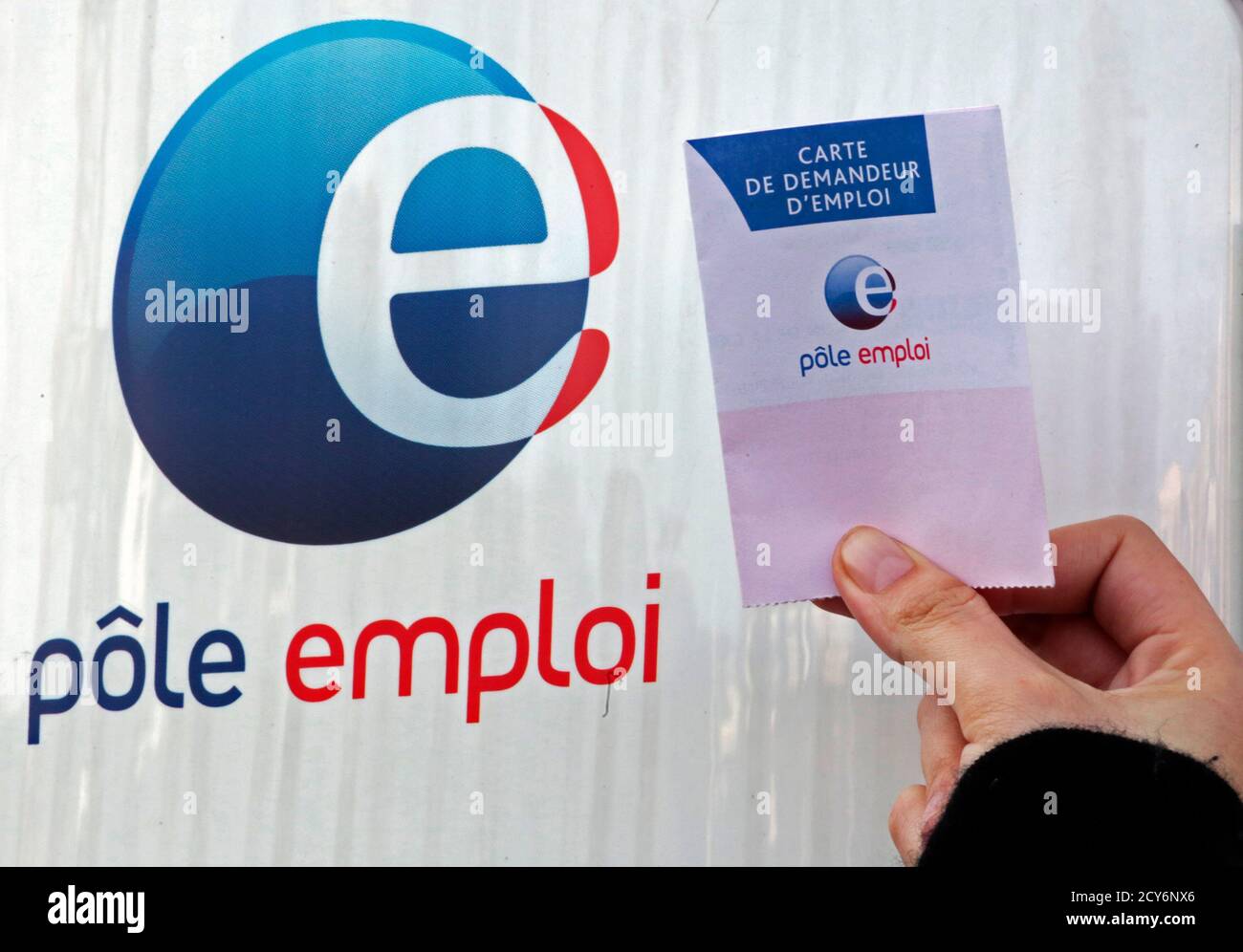 A woman displays her job seeker's card outside a National Agency for  Employment (Pole Emploi), in Nice February 27, 2013. The number of people  out of work in France shot up again