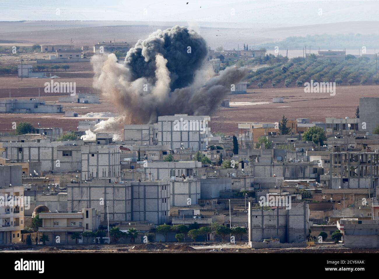 Smoke rises from the Syrian town of Kobani, seen from near the Mursitpinar border crossing on the Turkish-Syrian border in the southeastern town of Suruc in Sanliurfa province October 15, 2014. American-led forces conducted 21 airstrikes near Kobani, Syria, in the last two days to slow the advance of Islamic State militants, the U.S. military said on Tuesday, warning the situation on the ground is fluid as militants try to gain territory. REUTERS/Kai Pfaffenbach (TURKEY - Tags: MILITARY CONFLICT POLITICS) Stock Photo