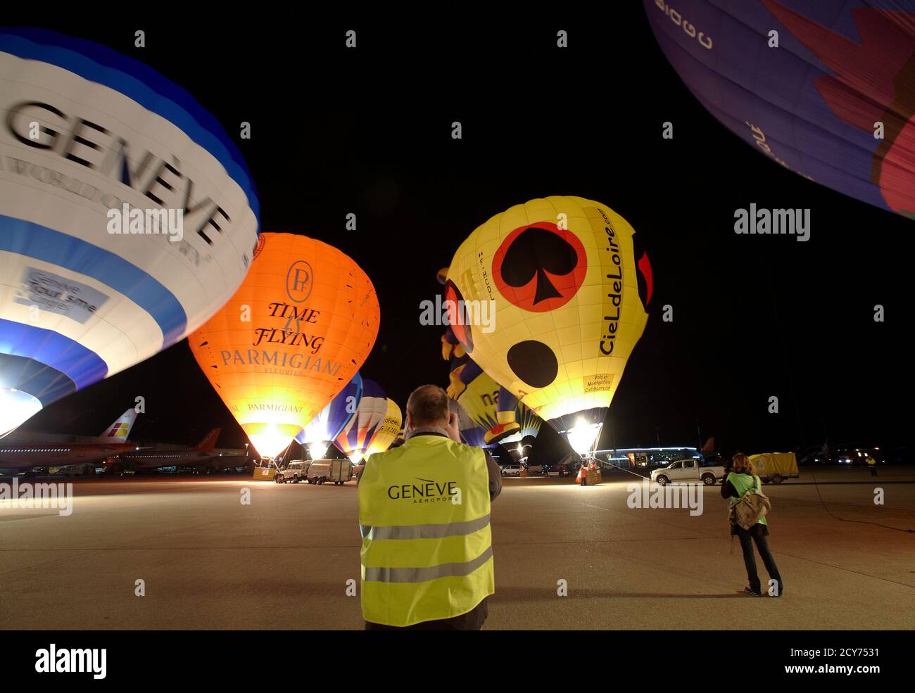 Photographers take pictures of hot air balloons during the night glow event of the sixth Montgolfiades Festival at Cointrin International Airport in Geneva late April 13, 2012. Thirty hot air balloons from nine countries will perform five flights between April 13 and 15, according to the organisers. REUTERS/Denis Balibouse (SWITZERLAND - Tags: TRANSPORT SOCIETY TRAVEL) Stock Photo