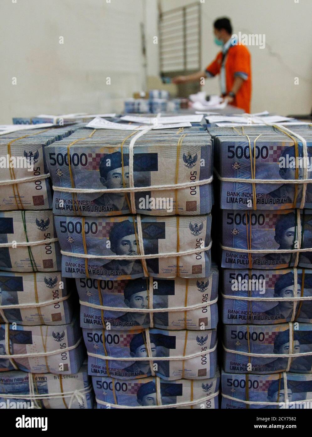 A bank employee sorts rupiah banknotes at the Bank National ...