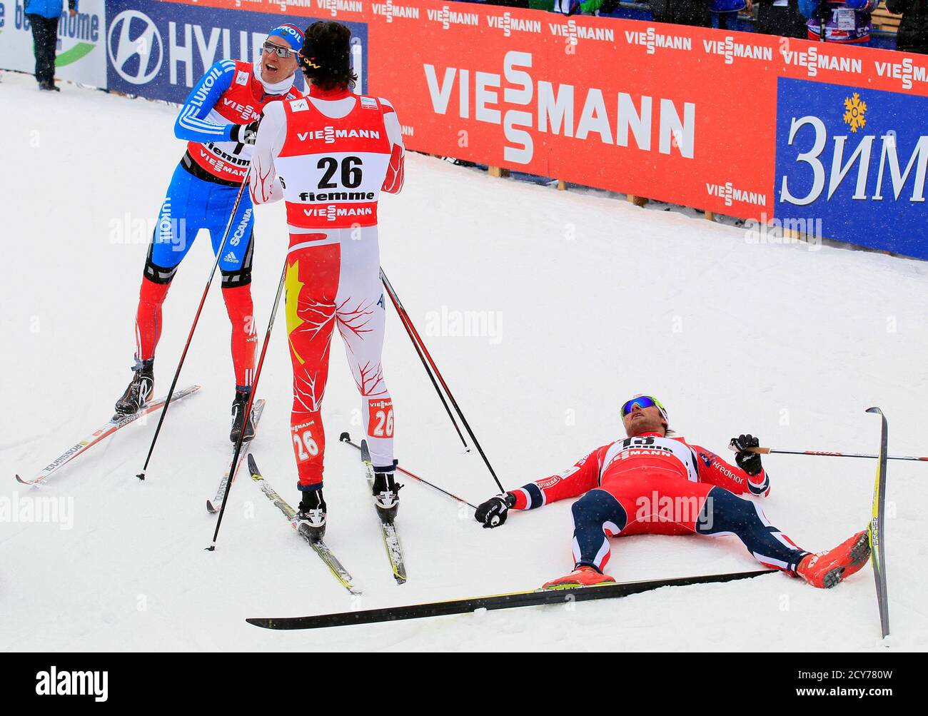 First placed Nikita Kriukov of Russia (L) is congratulated by third placed  Alex Harvey of Canada (C) as second placed Petter Jr. Northug of Norway (R)  lies down after the men's cross