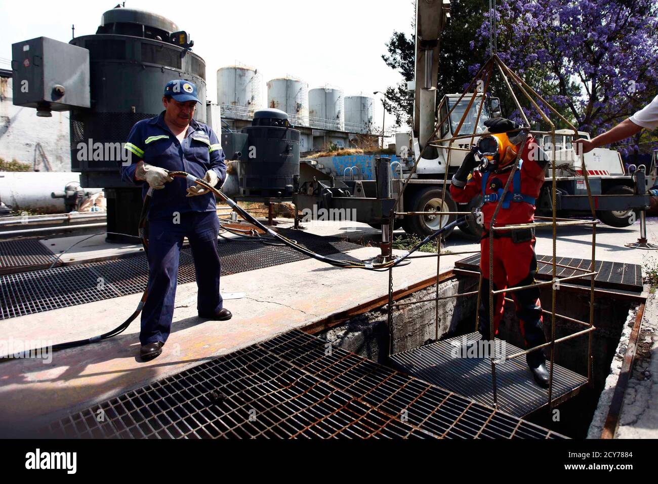 Mexican sewer diver Julio Cu Camara, 52, is lowered down in a cage before a dive at the city's drainage system plant in Mexico City March 21, 2013. Cu Camara's job involves diving in the city's sewage system to clear blockages and repair infrastructure, on an average of four times a month, for about 30 minutes to six hours depending on the amount of work needed. Cu Camara, who started working as a sewer diver 30 years ago, uses a diving suit and helmet that weigh more than 40 kg to protect him during his dives. During his working experience, he has found dead humans, horses, weapons and car pa Stock Photo