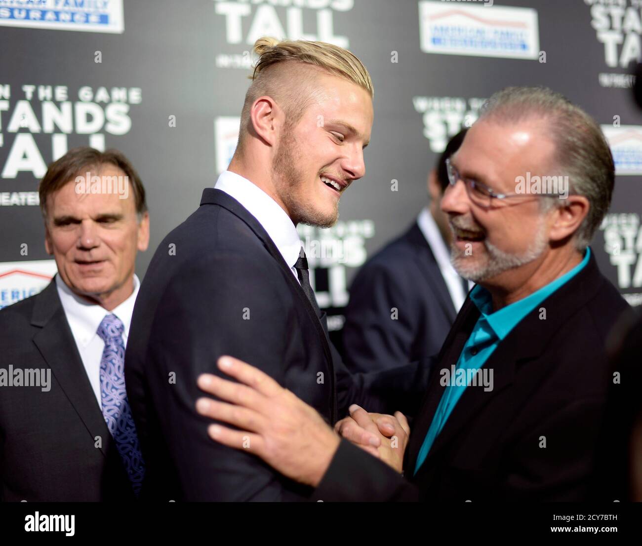 Cast member Alexander Ludwig (C) greets assistant football coach Terry  Eidson (R) as former football coach Bob Ladouceur looks on during premiere  of the film 