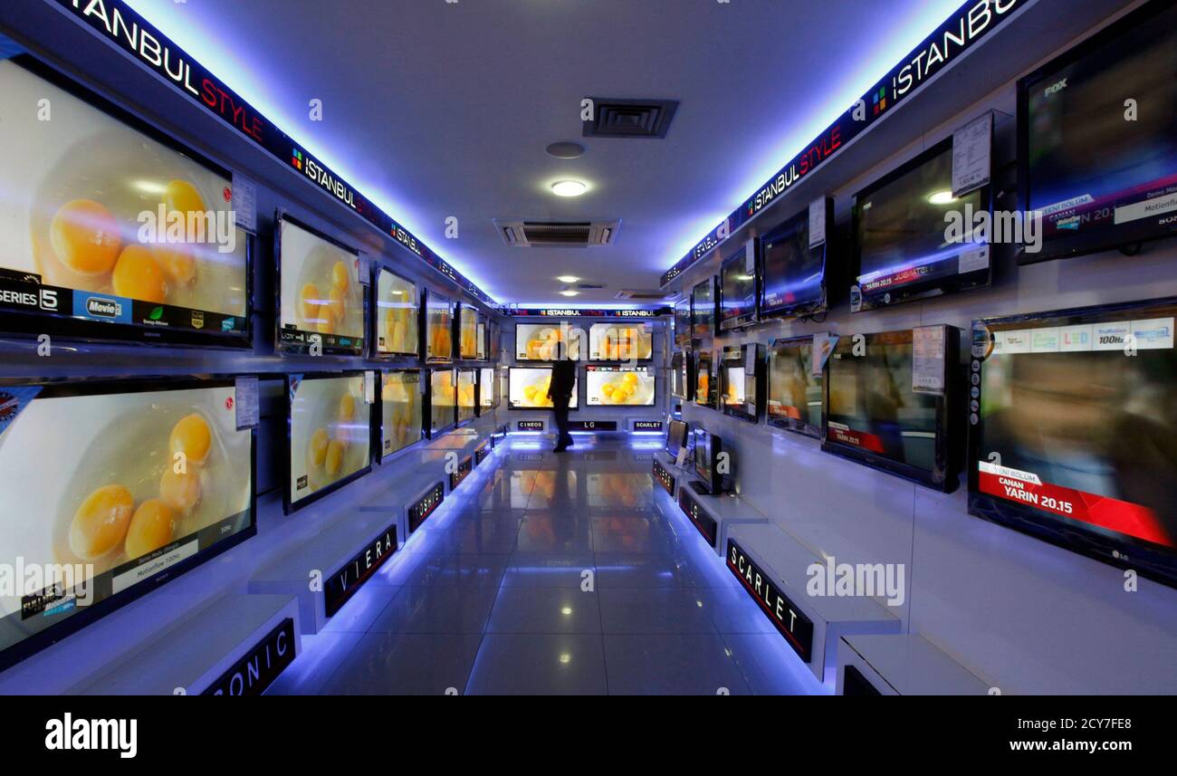 A customer looks at large screen televisions at a shop in March 8, 2011. Inside the electronics store wall-to-wall rows of imported flat- screen TVs switched to a commercial break in