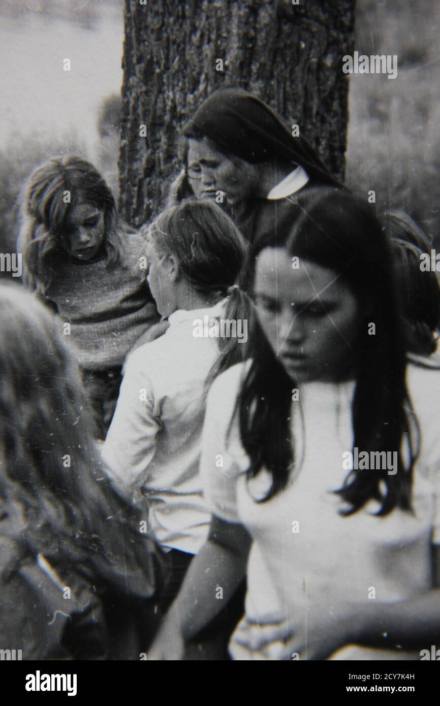 Fine 1970s vintage black and white photography of a Roman Catholic nun spending time with the children on a beautiful summer day. Stock Photo