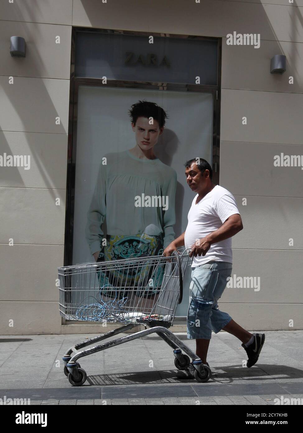 A man pushes a shopping trolley past a Zara store in Madrid June 13, 2012.  Spain's Inditex SA, the world's largest clothes retailer, bucked Europe's  financial crisis with a sharp rise in