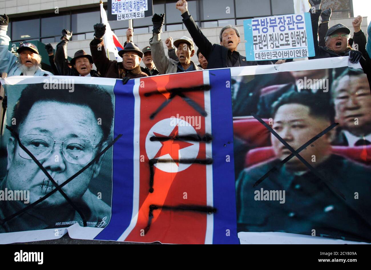 Protesters Shout Slogans With Defamed Portraits Of North Korean Leader Kim Jong Il L And His Son Kim Jong Un And North Korea S Flag At A Rally Denouncing North Korea S Artillery Shells Attack On