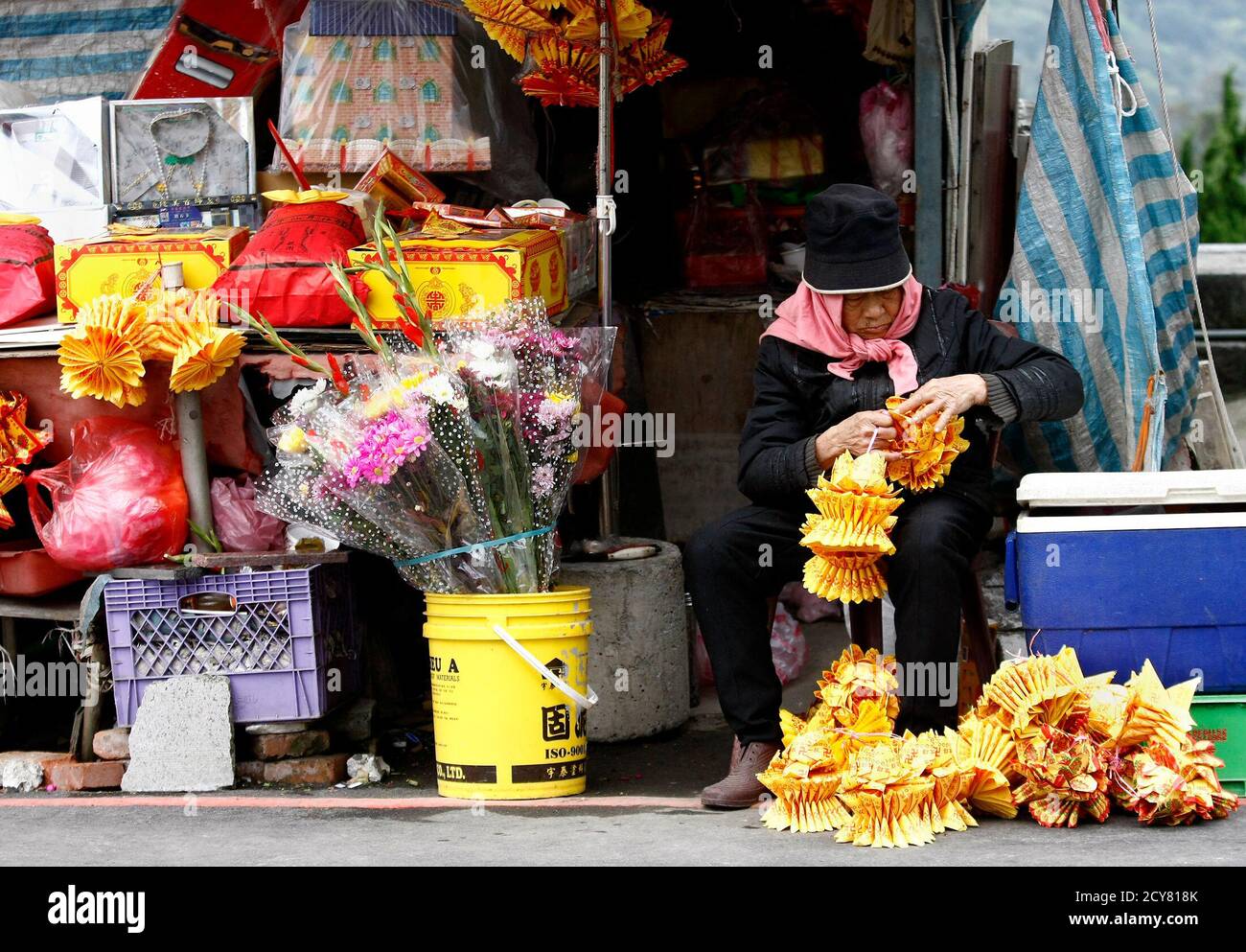 A vendor folds paper money in the shape of lotus used as offerings to
