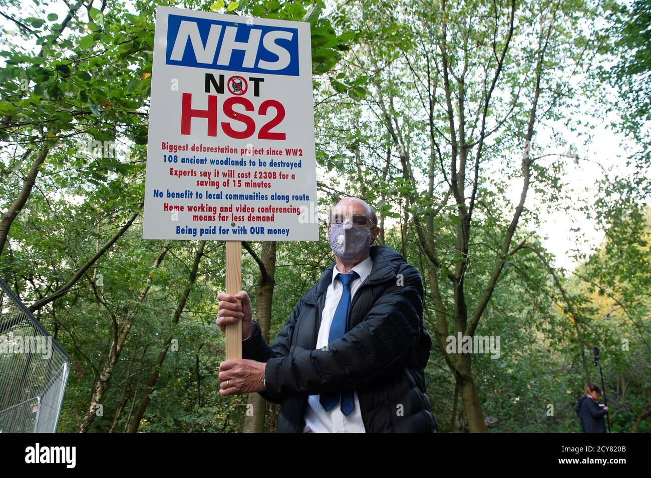 Wendover, UK. 1st October, 2020. A protester holds up an NHS not HS2 sign in the woods. Peaceful tree protectors and environmental campaigners at the Stop HS2 Jones Hill Protection Camp were being evicted today from their homes in the trees by the National Eviction Team Enforcement Agents working on behalf of HS2 Ltd. The over budget and controversial HS2 High Speed Rail link from London to Birmingham project puts 108 ancient woodlands, 693 wildlife sites and 33 SSSIs at risk of damage or destruction. Maureen McLean/Alamy Live News Stock Photo