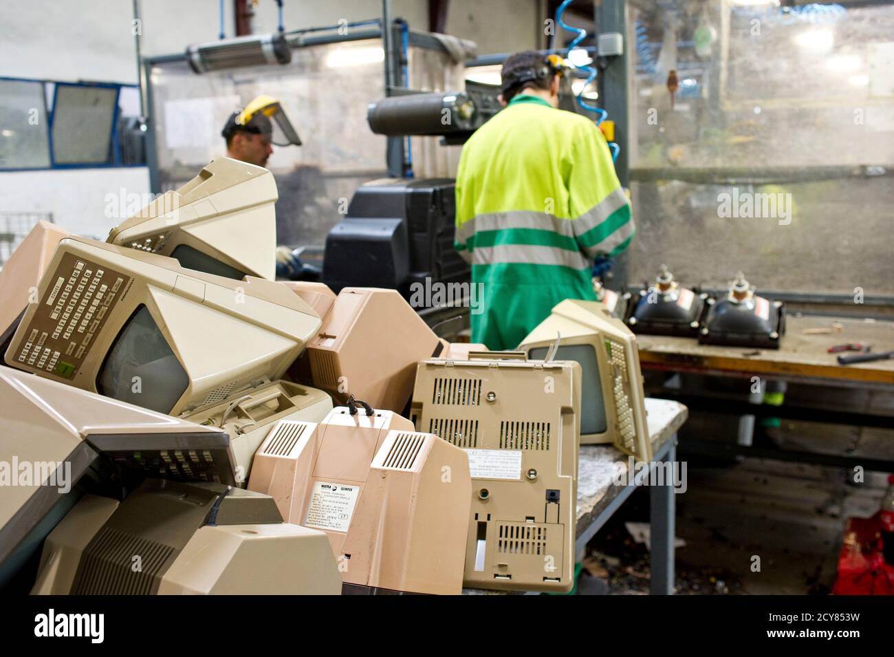 A man works behind a stack of French Minitel terminals which are to be broken down into its components for recycling in Portet-Sur-Garonne, southwestern France May 23, 2012. The Minitel, the box-like terminal with a keyboard and monochrome screen, was introduced on the market in 1982 by telecommunications operator France Telecom and used by the French to get information as a phone directory or to purchase train tickets. Although there are between 600,000 - 700,000 of the units still in use, the Minitel service will end on June 30, 2012.   REUTERS/Bruno Martin   (FRANCE - Tags: SCIENCE TECHNOLO Stock Photo