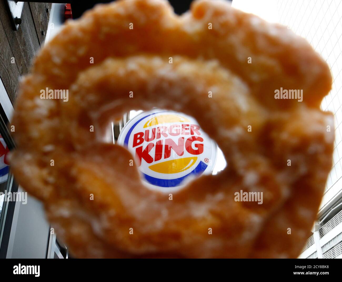 The Burger King logo is seen through a Tim Horton's doughnut hole in a photo illustration outside a restaurant in Toronto August 29, 2014. Burger King's proposed $11.5 billion acquisition of Canada's Tim Hortons may offer big tax benefits to the U.S. fast food chain but the real tax winner is likely to be its controlling shareholder, 3G Capital. The New York investment firm is not only deferring a capital gains tax hit in the U.S. because of the deal structure, but is also poised to reap a multitude of dividend tax and other benefits by moving Burger King's domicile to Canada, tax experts on b Stock Photo