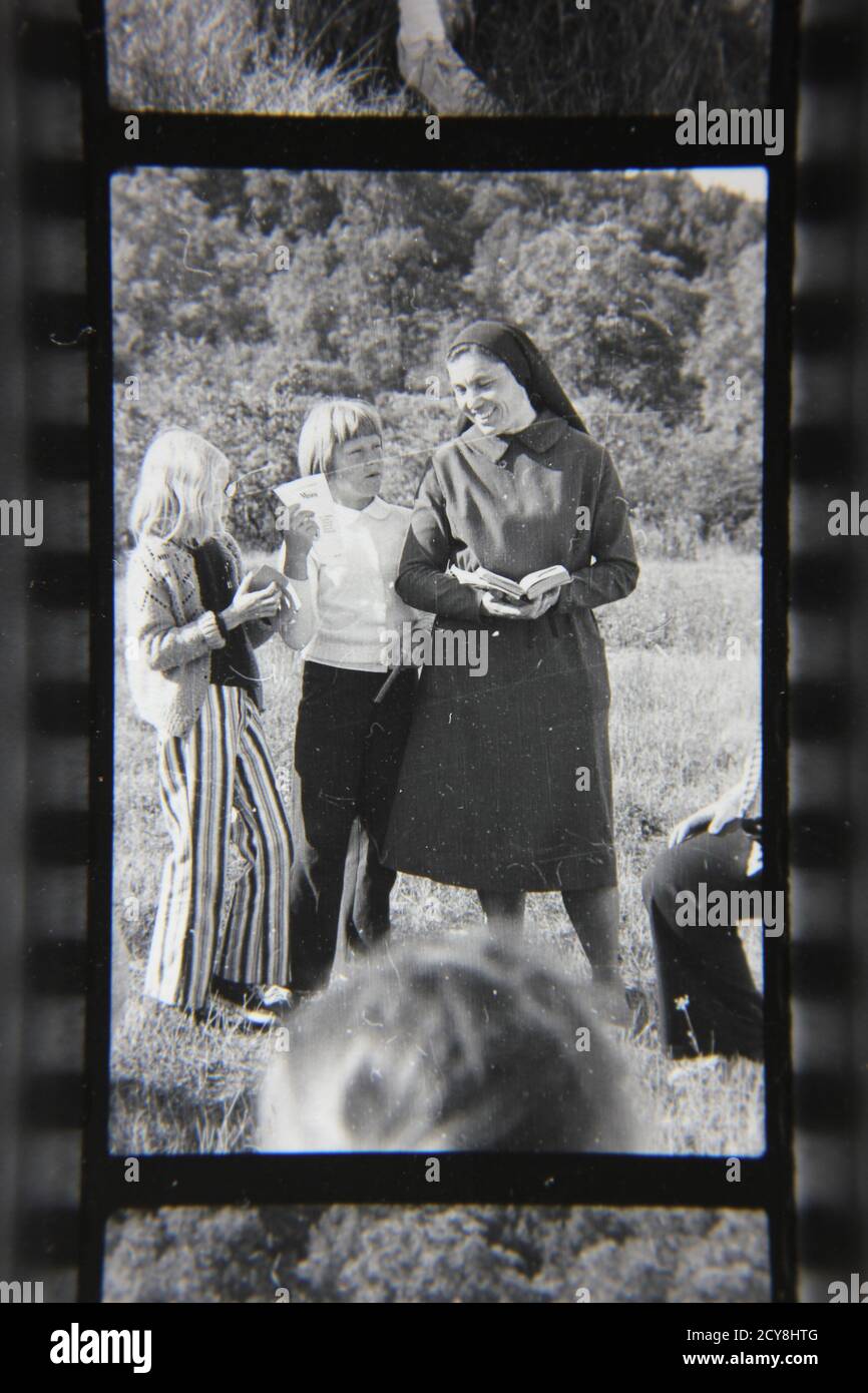 Fine 1970s vintage black and white photography of a Roman Catholic nun spending time with the children on a beautiful summer day. Stock Photo