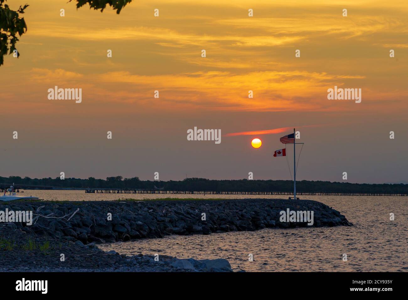 The Canadian and American flag fluttering side by side at sunrise. Stock Photo