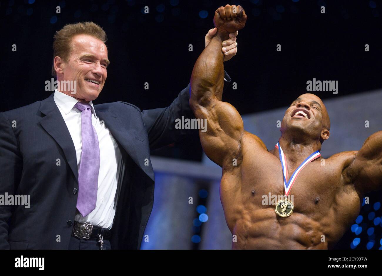 Former champion bodybuilder and former California governor Arnold Schwarzenegger (L) raises the arm of Dominican bodybuilder Victor Martinez after he won the inaugural Arnold Europe bodybuilding event in Madrid October 8,
