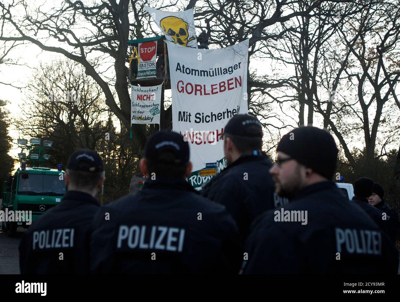 An activist from the environmental organization Robin Wood observes the police from his tree house in Langendorf near Gorleben November 28, 2011. The controversial shipment of 11 Castor containers with spent German nuclear fuel reprocessed in France, will be loaded onto trucks in Dannenberg before its final transportation to the nearby intermediate storage facility in the northern Germany village of Gorleben. The banner reads: "Radioactive waste storage Gorleben is not safe". REUTERS/Alex Domanski (GERMANY - Tags: ENVIRONMENT POLITICS CIVIL UNREST) Stock Photo