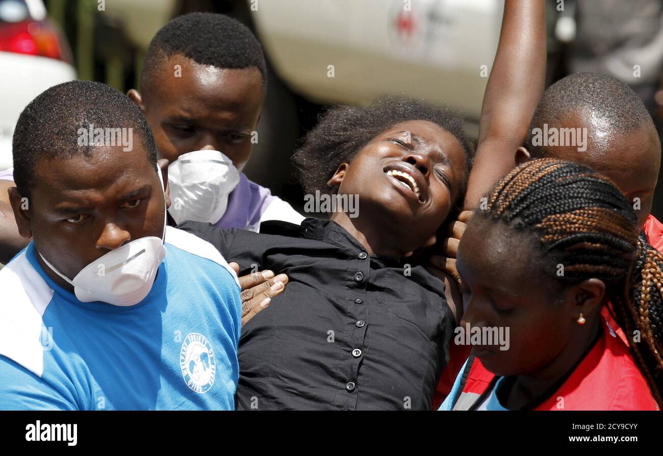 A relative is assisted by Kenya Red Cross staff where bodies of the students killed in Thursday's attack by gunmen, are preserved at the Chiromo Mortuary in the capital Nairobi April 4, 2015. Somali militants vowed on Saturday to wage a long war against Kenya and run its cities 'red with blood' after the group's fighters killed nearly 150 people during an assault on a Kenyan university. REUTERS/Thomas Mukoya Stock Photo