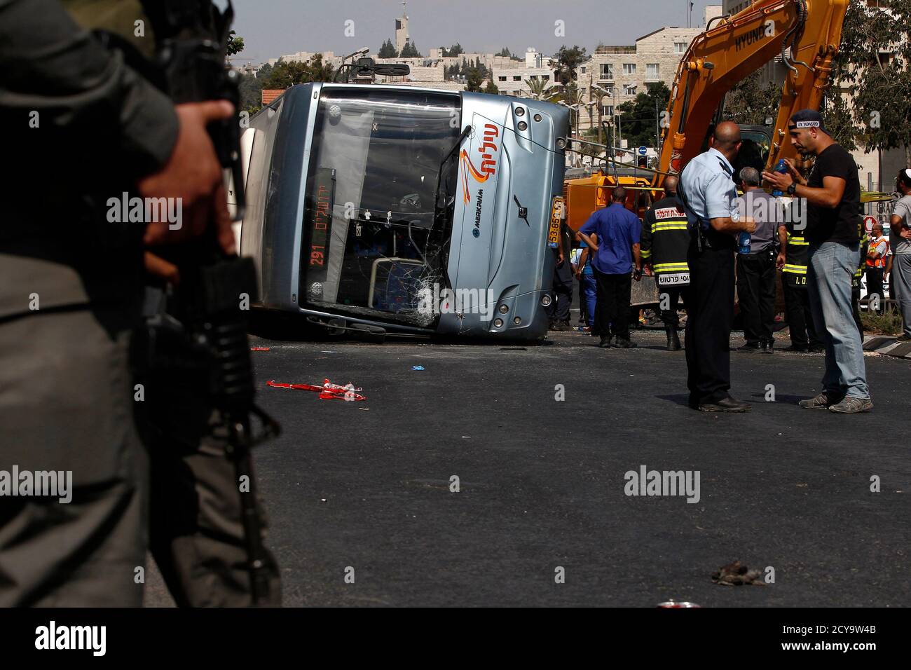 Israeli policemen stand next to an overturned bus at the scene of a suspected attack in Jerusalem August 4, 2014. A Palestinian used his heavy construction vehicle to run down and kill an Israeli and overturn the bus on a main Jerusalem street on Monday in attacks that ended when policemen shot him dead, police said. REUTERS/Siegfried Modola (JERUSALEM - Tags: POLITICS CIVIL UNREST TPX IMAGES OF THE DAY) Stock Photo