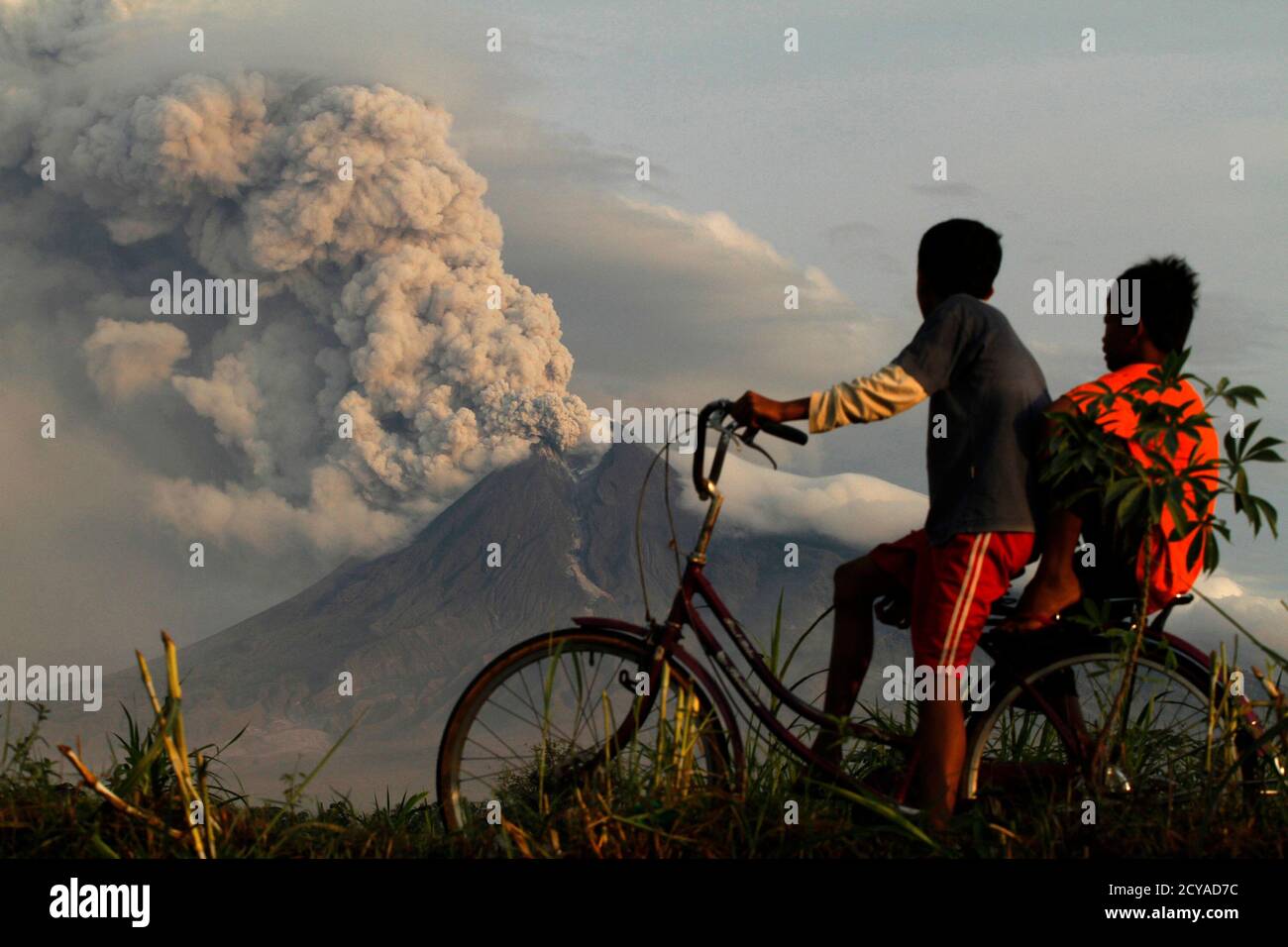 Boys look at the eruption of Mount Merapi volcano in Manisrenggo village, in the Klaten district of Indonesia's central Java province November 10, 2010. Mount Merapi showed lethargic signs on Wednesday but authorities would not lower down its alert status because of its intense seismic activities, the head of the country's vulcanolology agency said. REUTERS/Andry Prasetyo (INDONESIA - Tags: DISASTER ENVIRONMENT IMAGES OF THE DAY) Stock Photo