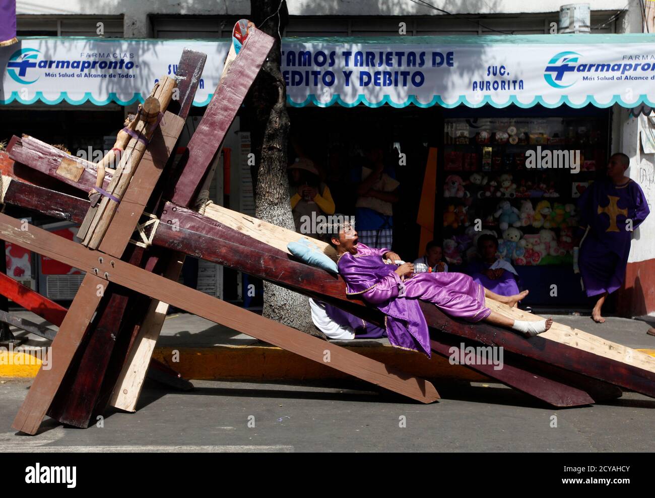 A penitent yawns while resting on crosses to be used during a re-enactment of the crucifixion of Jesus Christ on Good Friday in Iztapalapa in Mexico City April 6, 2012.    REUTERS/Edgard Garrido (MEXICO - Tags: RELIGION ANNIVERSARY SOCIETY) Stock Photo