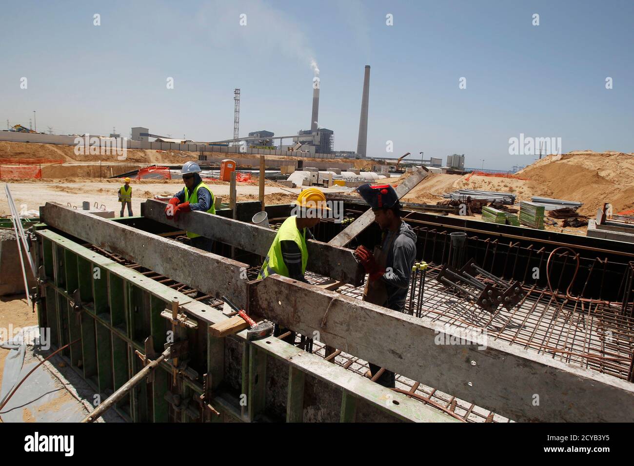 Labourers work at the construction site of Dorad, a private power plant in the southern city of Ashkelon May 17, 2012. Israel Electric Corp (IEC), which is responsible for nearly every aspect of electricity from running power plants to connecting households, simply cannot keep up with growing demand.The state-owned utility just lost natural gas supplies from neighbouring Egypt and fuel costs are soaring. Reserves are low and capacity insufficient and the government, under pressure from massive cost-of-living protests, has limited how much it can charge the public for electricity consumption. P Stock Photo
