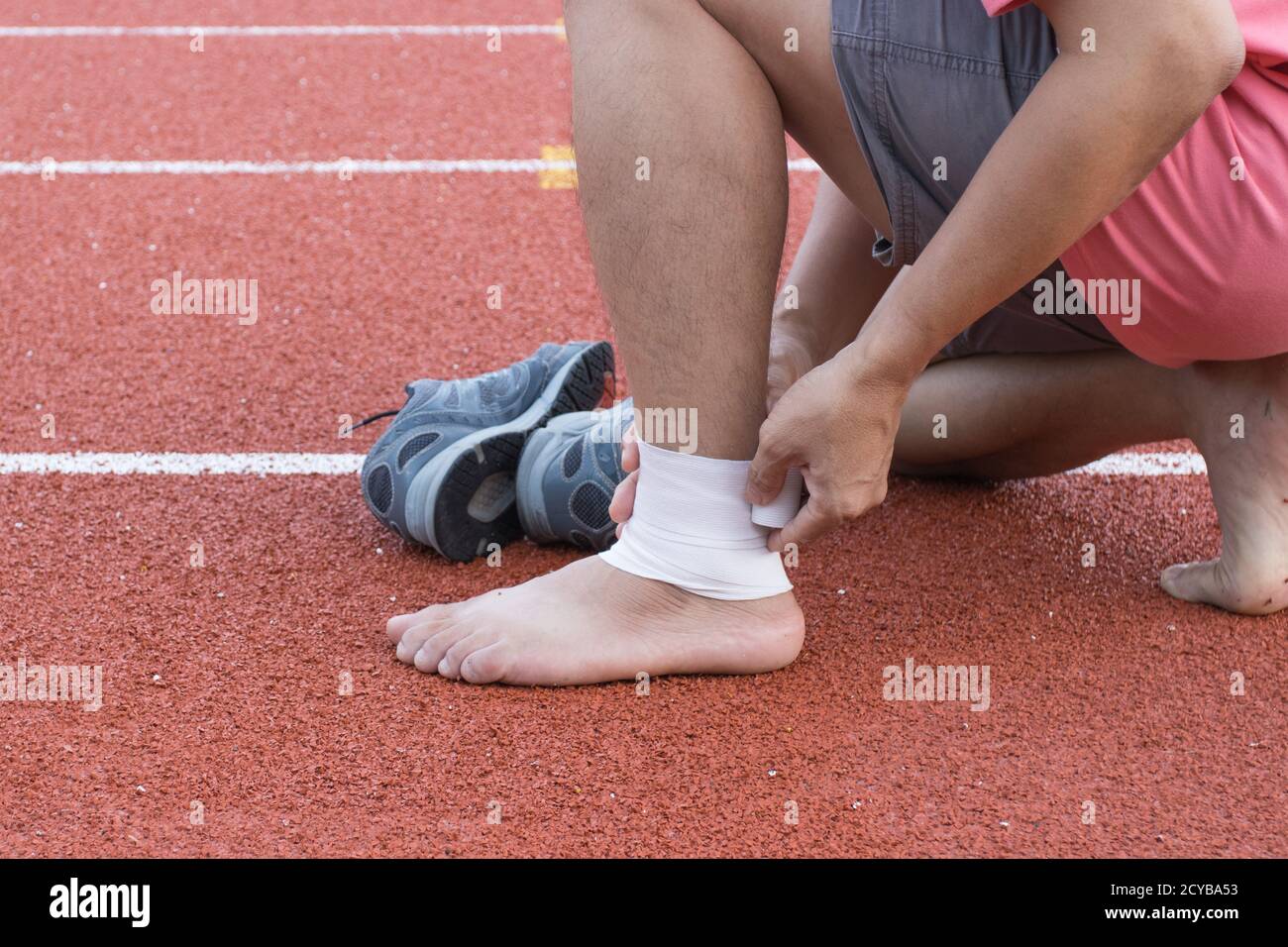 man applying compression bandage onto ankle injury of a football player