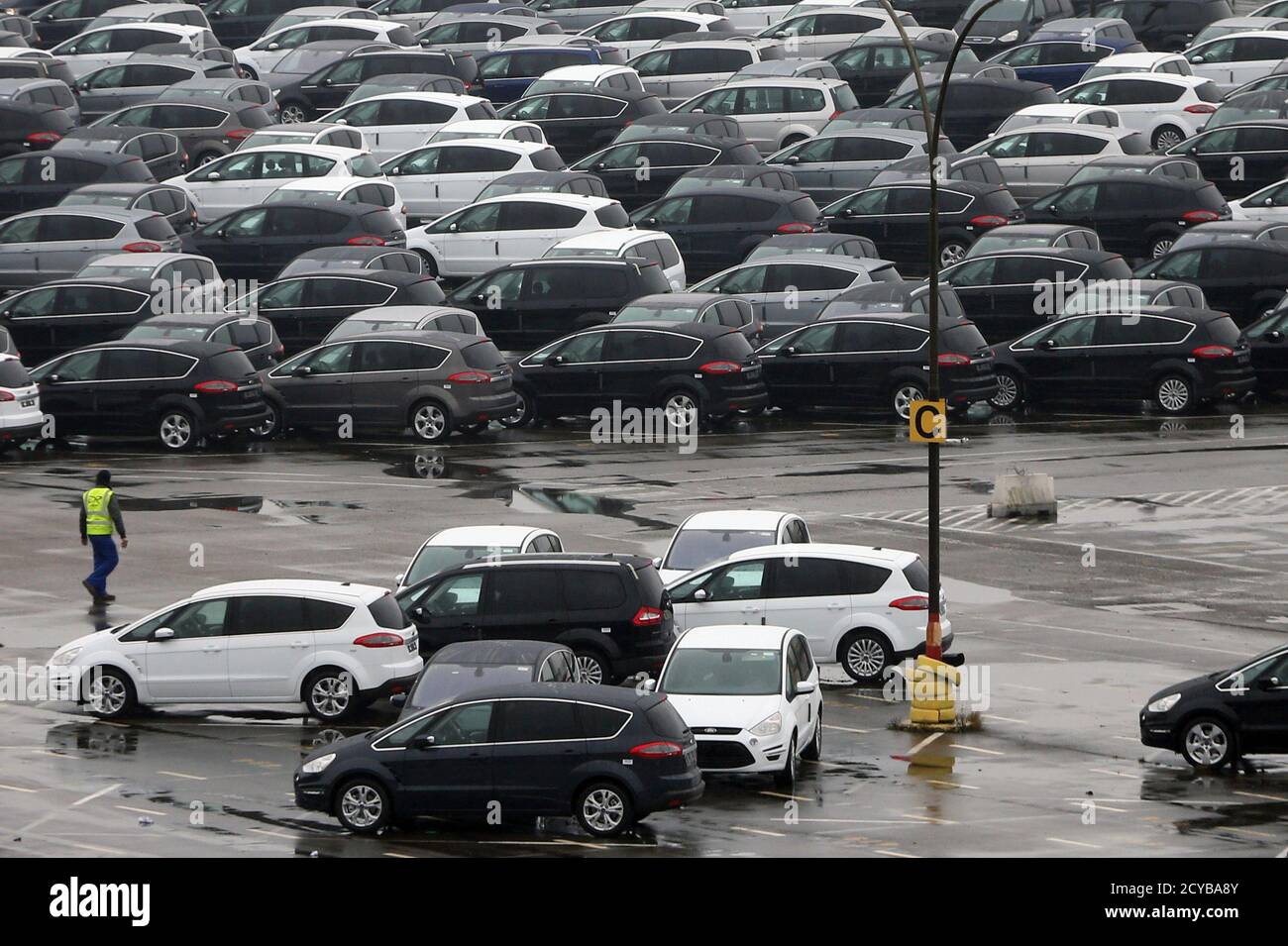 A worker walks by Ford vehicles in a parking lot at the Ford assembly plant in Genk December 17, 2014. In the heart of western Europe, the Belgian-Dutch-German rust belt has been dealt another blow. Two car plants closed this month as companies sought cheaper labour elsewhere, the final chapter of a manufacturing boom that began when coal mines fuelling Europe's industrialisation shut in the 1960s. Now the region straddling three borders is trying to reinvent itself. A 315 billion euro EU investment plan, announced on Thursday, is the latest potential help. It aims to encourage investors to ba Stock Photo