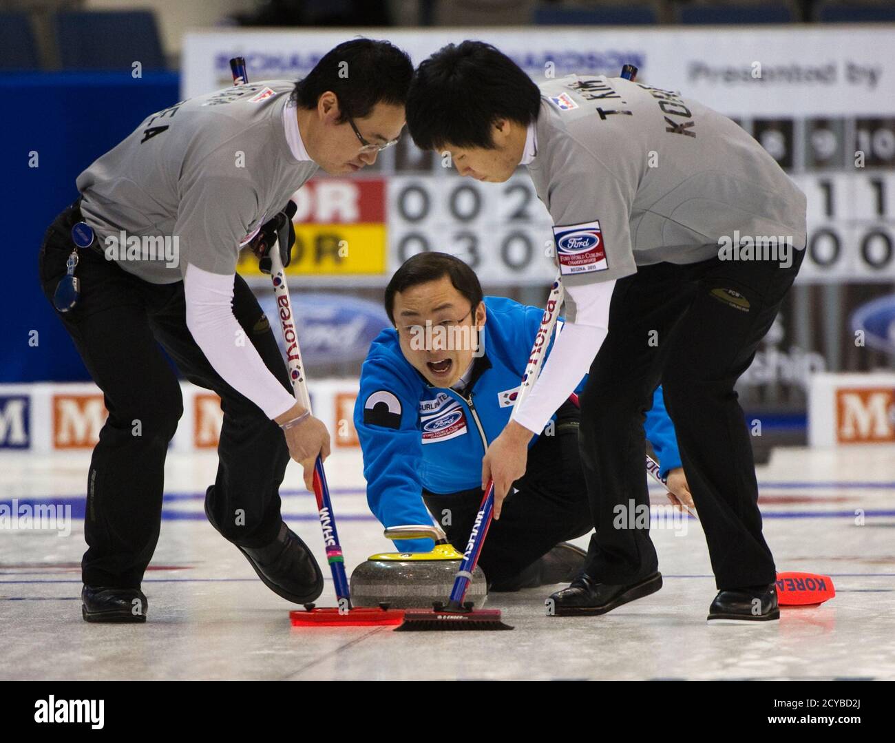 South Korea's skip Lee Dong-keun (C) shouts to teammates Nam Yoon-ho (L)  and Kim Tae-hwan to sweep during play against Norway at the World Men's  Curling Championships in Regina, Saskatchewan April 2,