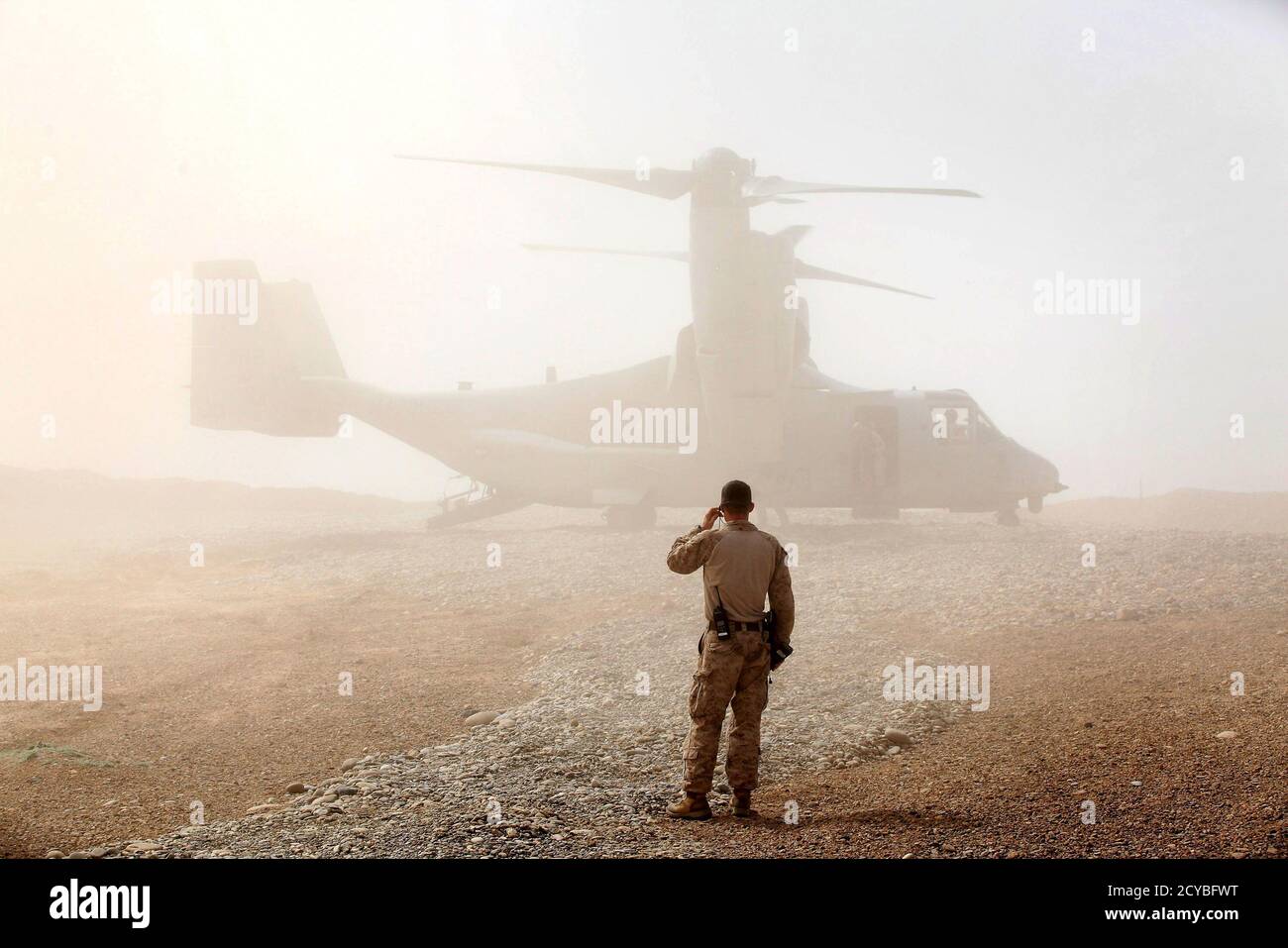 A U.S. Marine watches as an Osprey carrying U.S. Defense Secretary Leon Panetta arrives at Forward Operating Base Shukvani, Afghanistan March 14, 2012. Panetta told troops in Afghanistan on Wednesday that the massacre of 16 Afghan civilians by an American soldier should not deter them from their mission to secure the country ahead of a 2014 NATO withdrawal deadline.  REUTERS/Scott Olson/Pool (AFGHANISTAN - Tags: POLITICS MILITARY TPX IMAGES OF THE DAY) Stock Photo